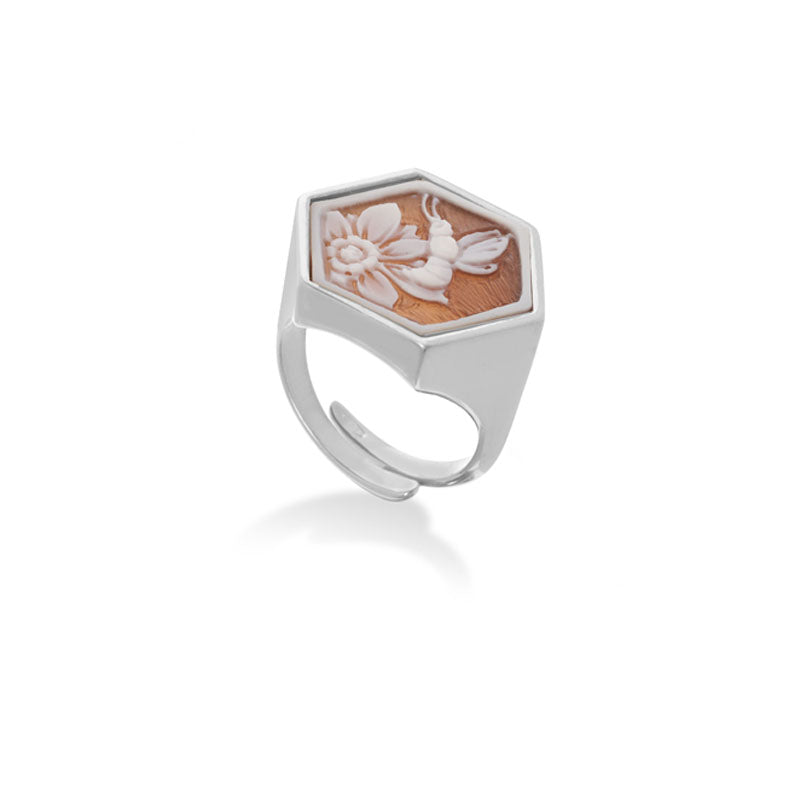 Articolo: Anello Cammeo Esagonale con Incisa Ape della Speranza Materiale Struttura: Argento bianco rodiato 925  Superficie: incisa a mano perfetta ed integra Lucentezza: Molto alta Colore Cammeo: Rilievo Bianco Materiale Cammeo: Conchiglia Naturale Sardonica Incisione Cammeo: Ape della Speranza con Motivo Floreale Forma e dimensione Cammeo: Esagonale ±20mm Montatura: Fascia aperta regolabile in argento bianco 925