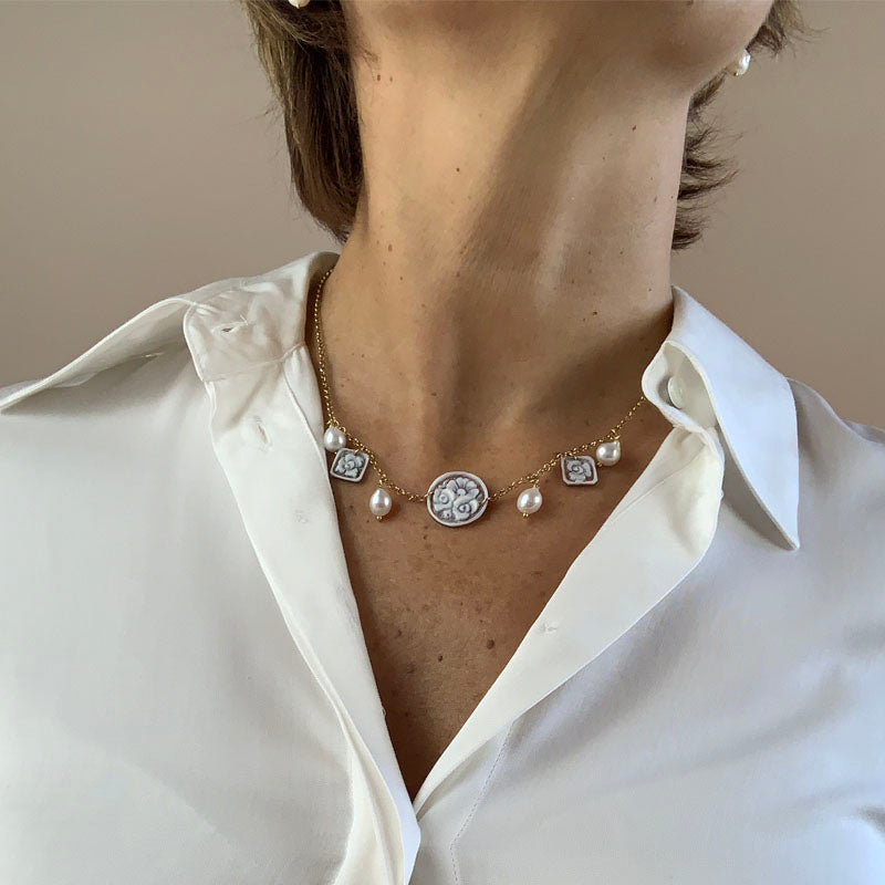 Collana Choker in argento 925% con Mini Cammei e Perle di Fiume pendenti. Cammeo Centrale tondo e Cammei laterali quadrati con motivi Floreali montati su Collana Catena Rolò in argento 925% colore oro, Nichel Free e Perle di fiume. Cammeo inciso a mano con cura e precisione con motivi Floreali su Conchiglia Sardonica, proveniente dal Bacino del Mediterraneo, per creare un effetto decorativo unico.